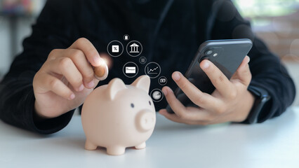 Person saving coin in piggy bank while using smartphone with virtual finance icons, representing mobile banking, digital saving, investment, and financial planning.