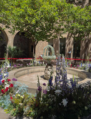 A decorative stone fountain in Catalonia features a dancing egg atop a water jet, surrounded by summer blooms as part of a Corpus Christi ritual.