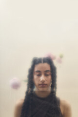 Young adult Caucasian woman with long braided hair standing with eyes closed, soft focus effect and...