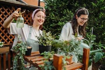 Two female friends or sisters taking care of plants with water can and mister	
