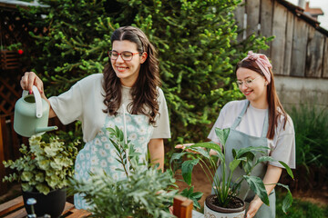 Two female friends or sisters taking care of plants with water can and mister	
