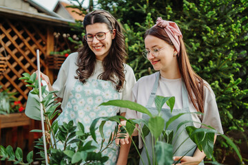 Two female friends or sisters taking care of plants with water can and mister	
