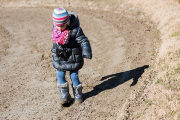 Little photographer walking carefully on muddy path