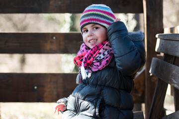 Smiling girl wearing winter clothes adjusting her knitted hat