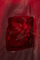 Closeup showing translucent red plastic sheet with square cutout revealing darker red area...