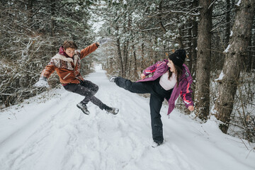Two friends engage in a fun and carefree moment in a snowy woodland setting, displaying energy and...