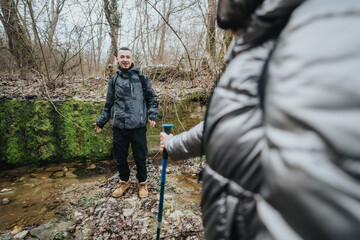 A hiker pauses near a serene stream surrounded by lush vegetation in a quiet woodland, perfectly...