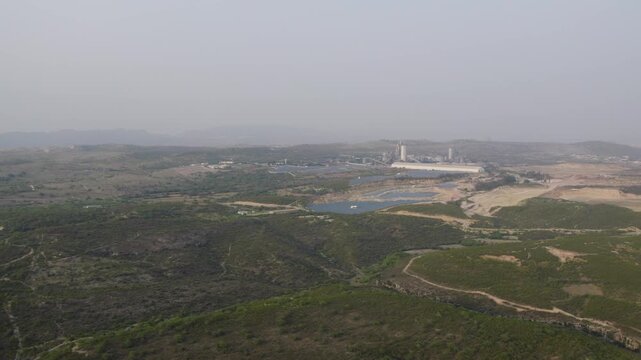 Wide aerial view of Swaik Lake, industrial site, green hills at Kallar Kahar. Punjab, Pakistan