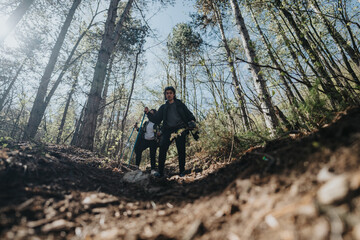 A couple enjoying a hike together in a forested area, surrounded by tall trees and sunlight...