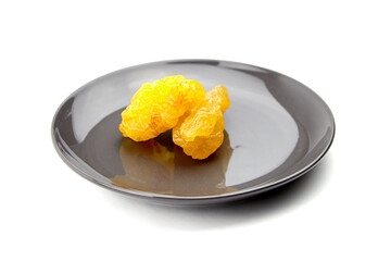 Dried dehydrated pear fruits arranged on a sleek black plate, showcasing their vibrant yellow color and unique texture, perfect for culinary presentations or healthy snacks
