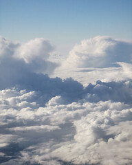 Expansive view of fluffy white clouds against a clear blue sky, showcasing the beauty of nature from above, creating a serene and tranquil atmosphere for relaxation