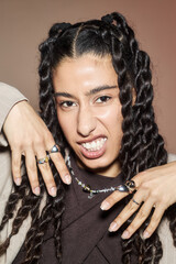Portrait of young adult Middle Eastern woman with long braided hair showing hands adorned with...
