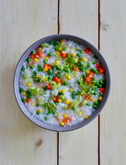 rice congee prepared with carrot, peas, and corn, isolated