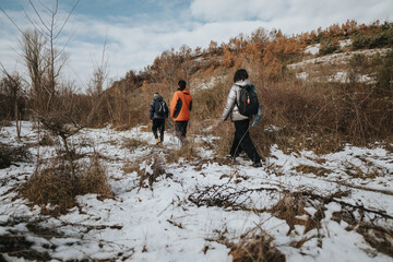 Three people hike through a snowy and scenic pathway surrounded by natural terrain and winter...