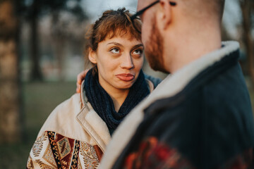 A couple sharing a humorous and endearing interaction outdoors, highlighting affection and...