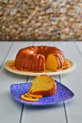 yellow bundt cake topped with an orange flavored glaze, slice on plate