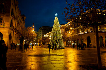Festive evening in Pamplona with beautifully illuminated Christmas tree and lively atmosphere in...