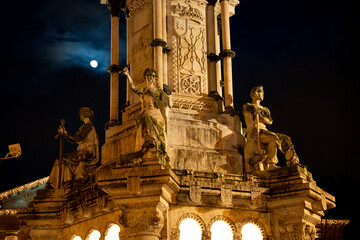 Monumento a los Fueros illuminates Pamplona Navarra at night with a glowing moon in the sky