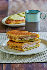 Cuban sandwich with ham, pork, swiss cheese and pickles, open faced sandwich in background