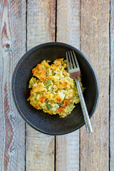 zucchini casserole topped with breadcrumbs and shredded cheese, fork in bowl