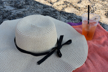 Summer layout with a sun hat and a drink on a beach towel. Aperitif cocktail. Vacation, travel and...