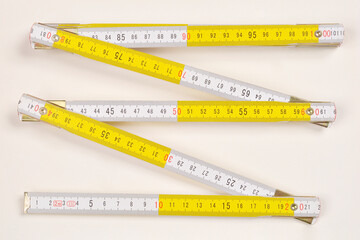 An unfolded yellow and white folding ruler with black markings lies on a light surface, showing...