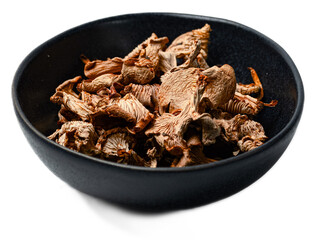 Assorted dried wild forest mushrooms including chanterelles and porcini in a black bowl showcasing organic dehydrated fungi for culinary use