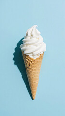 A vanilla ice cream cone with a shadow on a light blue background in a studio shot overhead view