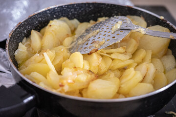 Spanish omelette preparation with sliced potatoes frying in a pan