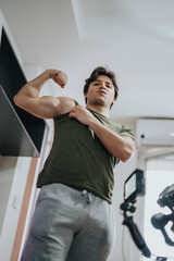 A man in athletic casual wear is confidently flexing his muscles in a bright, modern indoor space,...