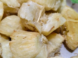 Fried cassava, golden yellow in color and crispy texture can be seen filling the entire frame, showing details of the fibers and soft inside