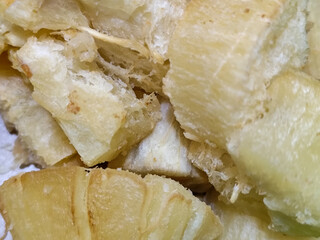 Fried cassava, golden yellow in color and crispy texture can be seen filling the entire frame, showing details of the fibers and soft inside