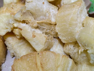 Fried cassava, golden yellow in color and crispy texture can be seen filling the entire frame,...