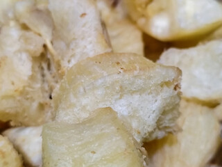 Fried cassava, golden yellow in color and crispy texture can be seen filling the entire frame, showing details of the fibers and soft inside