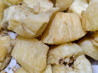 Fried cassava, golden yellow in color and crispy texture can be seen filling the entire frame, showing details of the fibers and soft inside
