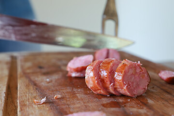 Sliced sausage arranged on a wooden surface, highlighting its juicy texture and rich, smoky color. The close-up reveals the seasoning and grilled exterior, making it perfect for food, barbecue, and cu