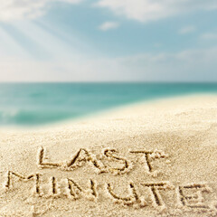Close-up of golden sand with last minute text drawn in the sand, space for product placement, turquoise sea and blue sky in tropical beach background – summer travel concept