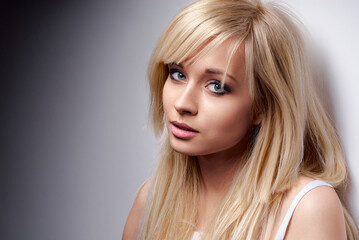 A close-up portrait of a young blonde woman with natural makeup and soft light, emphasizing beauty...