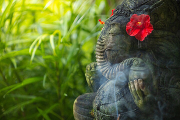 Elephant sculpture covered with green moss with ritual incense stick in Bali, Indonesia.