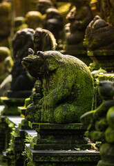 Old sculpture fully covered with green moss in Ubud's Monkey Forest. Bali, Indonesia.