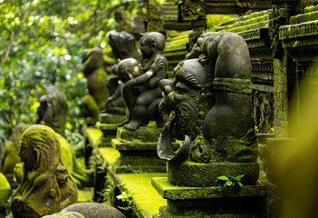 Old sculpture fully covered with green moss in Ubud's Monkey Forest. Bali, Indonesia.