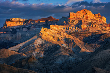 Early morning light illuminating a rugged mountain range, the warm colors of the sunrise casting long shadows and creating a breathtaking scene