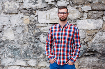 Portrait of a Man in Checkered Shirt Against a Stone Wall Outdoors
