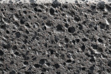 Surface of black volcanic rock with unique textures and patterns in natural lighting
