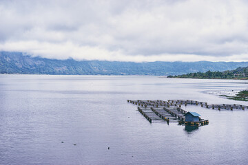 Tranquil Asian Lakeside View With Aquaculture Platforms Under Cloudy Sky