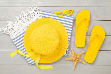 Beach towel with summer accessories on wooden background, top view