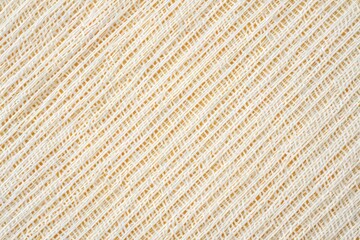 Abstract close up of a textured woven fabric with a diagonal pattern and a soft yellow background