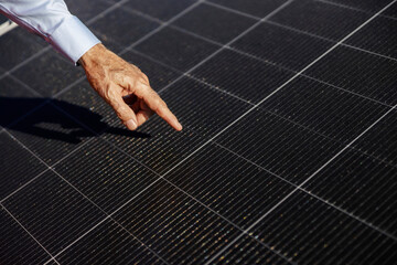 Senior man's hand pointing at solar panel.
