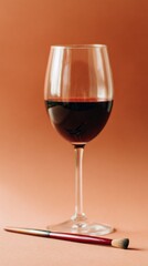 A sophisticated arrangement of a wine glass, brush, and palette set against a warm terracotta background creates a striking artistic display perfect for modern decor