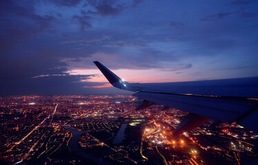 Wing of modern aircraft flying above Paris at night